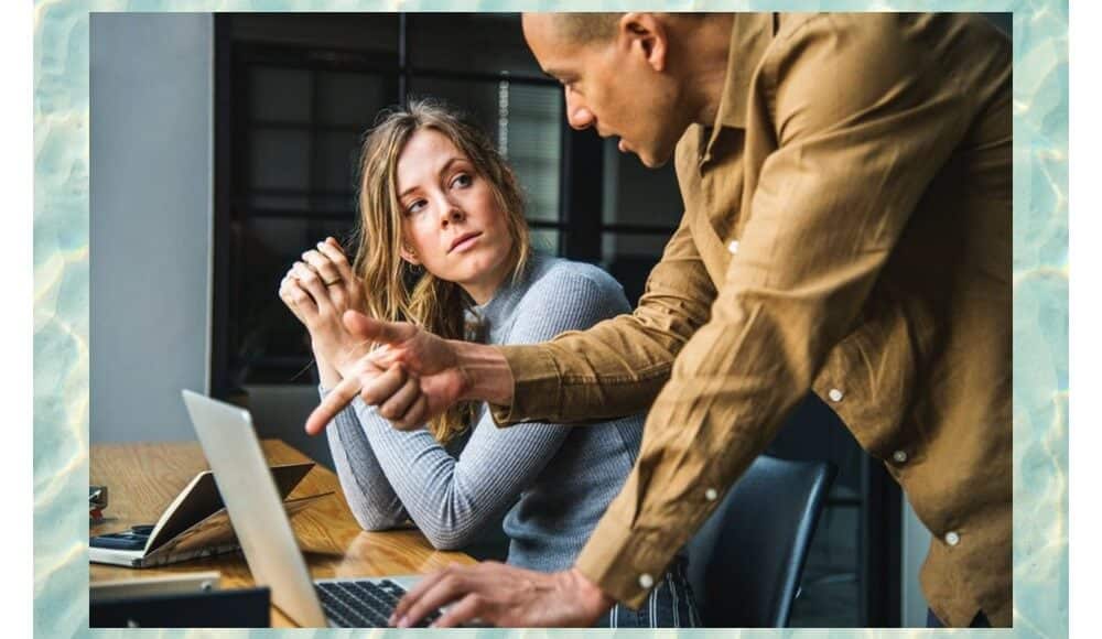 Removal of black magic, man and woman in front of a laptop discussing.