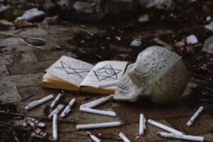 Signs of witchcraft, book with skull and candles on the ground.