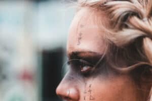 Woman sending evil eye symptom glare with black paint around her eyes.