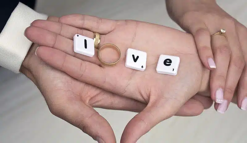 Compatibility test, man and woman hands on top of each other hold the word love.