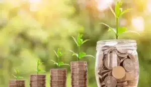 Good luck in business, glass jar with coins inside sprouting a plant.