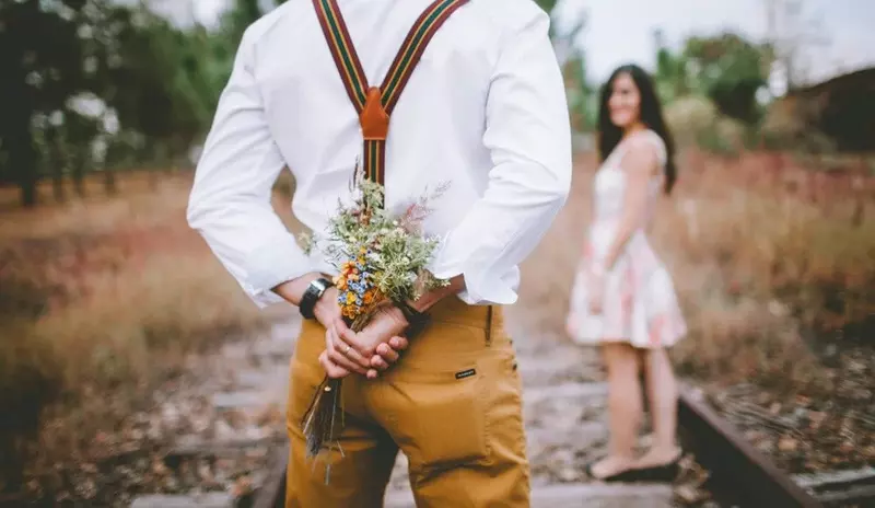 How to find a companion, man holding flowers behind his back.