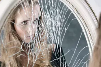 Remove curse, woman looking into a broken mirror.