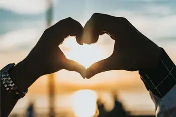 Love match, hands forming a heart in the sun.