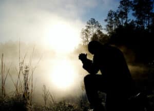 A man kneeled doing prayer for healing.