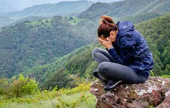 Remove black magic, woman sitting on mountain pouting.