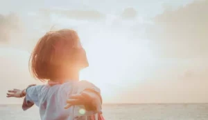 Soul cleansing, woman standing in front of a sea with her arms out.