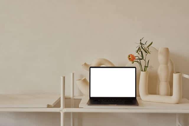 Laptop on a desk with candles behind it to make a payment.