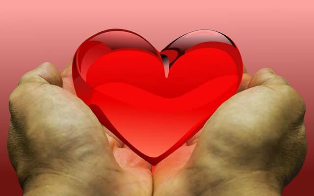 Male hands holding a red heart to donate to spiritual healing.