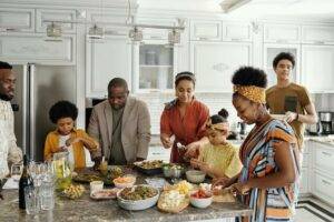 Family standing around kitchen laughing appreciating family and heath.