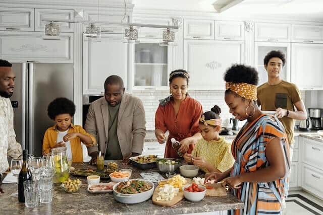 Family standing around kitchen laughing appreciating family and heath.