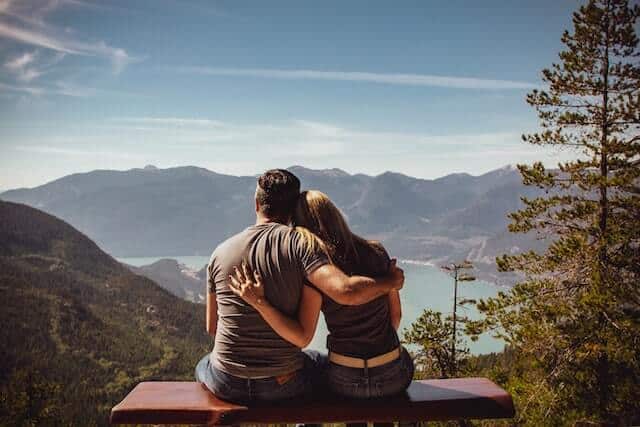 couple sitting on a mountain enjoying the sunny view having a healthy relationship.