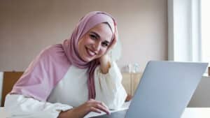 Muslim woman sitting in front of a laptop with positive energy.