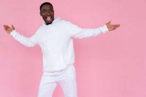 Man with positive energy wearing white standing in front of a pink background.