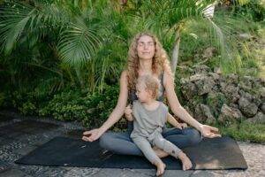 Woman sitting doing Yoga with girl on her lap with positive energy.