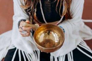 Remove negative energy from your aura, woman sitting with brass bowl.