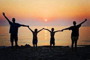 Signs of curse on family standing in front of the ocean sunset.