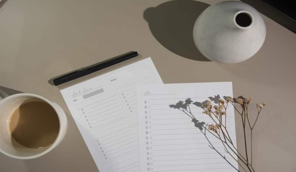 Spiritual assessment, paper checklist, with a half dranken coffee mug and a vase on a table.