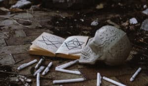 Signs of black magic. Skull, spell book and candles on the ground.