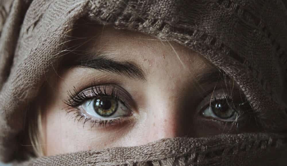 Signs of evil eye, woman's eyes with brown head cover