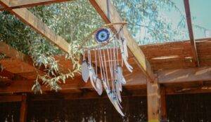 Signs of Evil Eye pendant hanging from the ceiling with feathers.