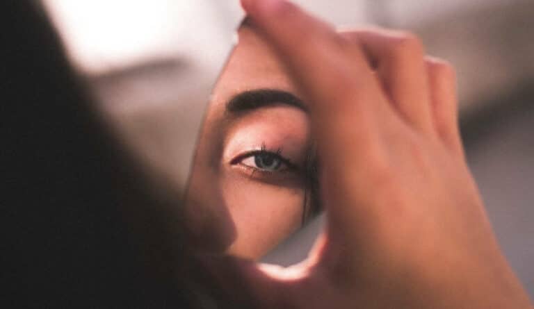 Woman looking in broken mirror looking to breaking curses.