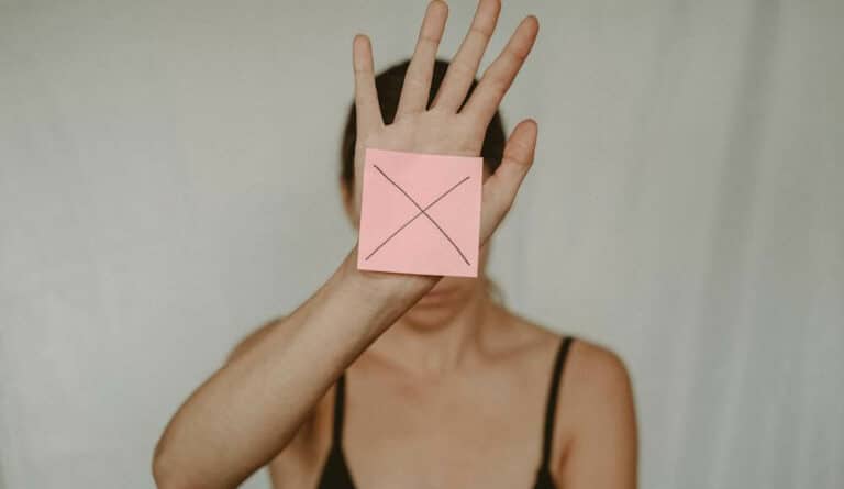 A woman with a pink sticky note on her hand with an x on it. Learning what causes bad luck in life.