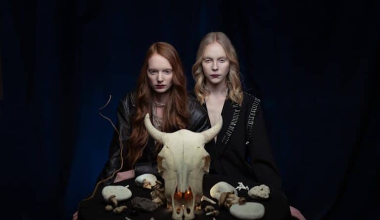 2 witched standing behind a cow skull sending symptoms of witchcraft.