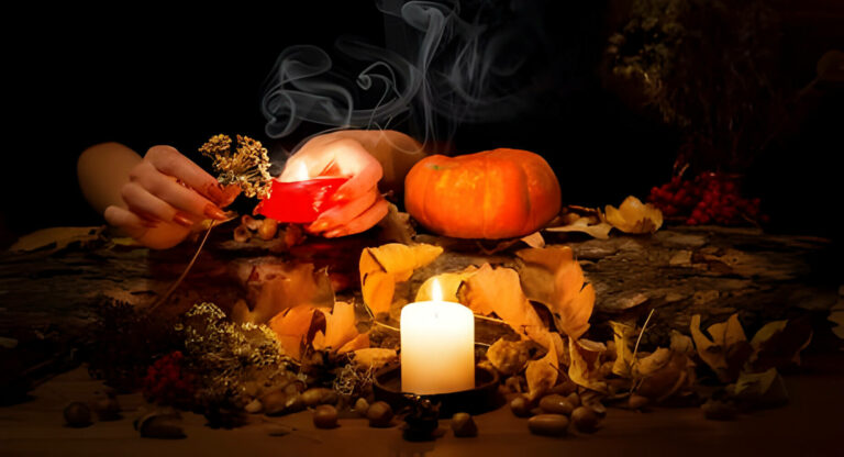 Pumpkins on leaves outside behind a lite white candle. What is black magic.